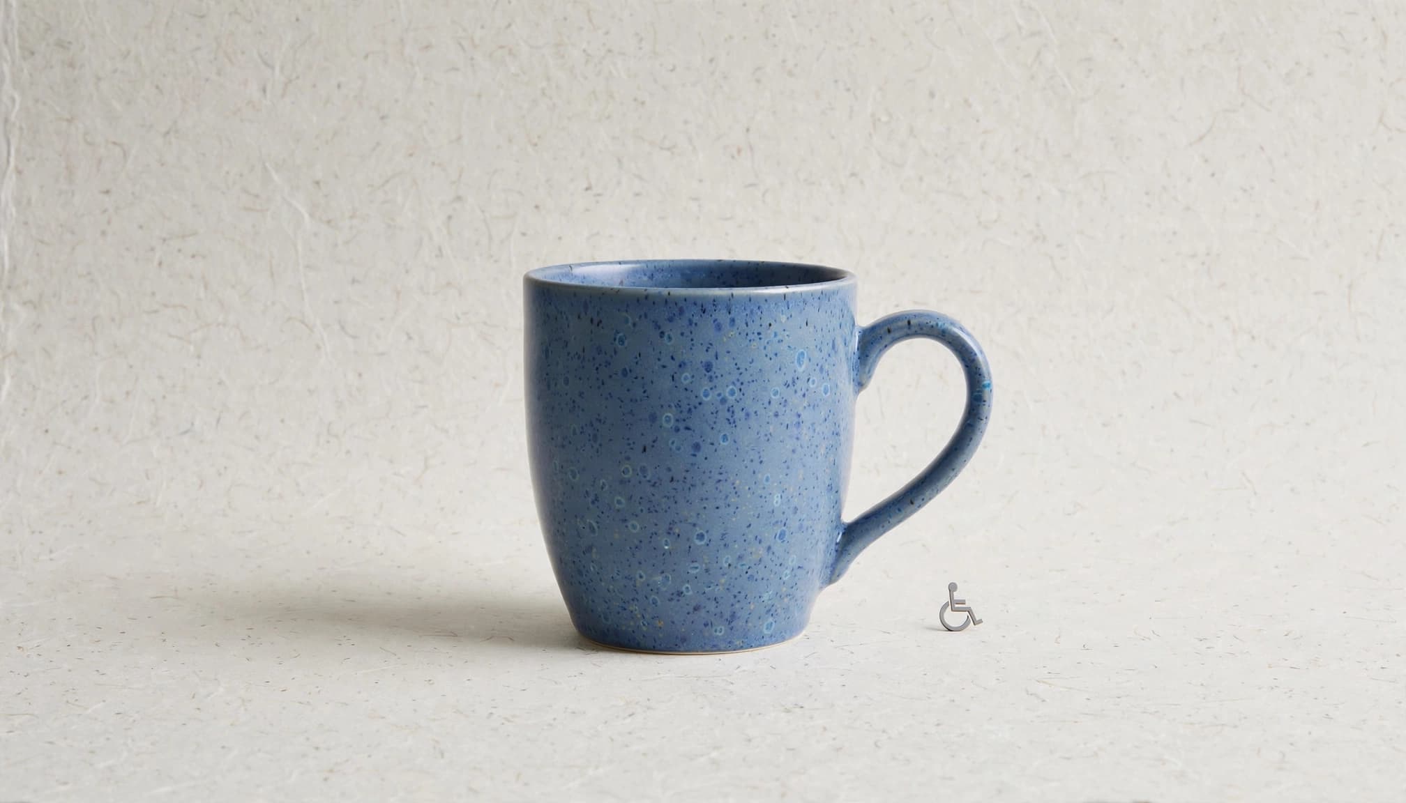 Blue ceramic mug beside an accessibility symbol.